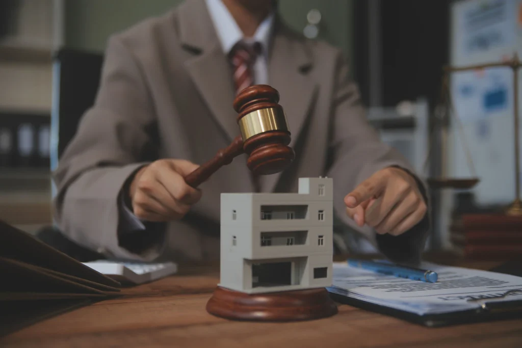 a person raises a gavel above a small model house